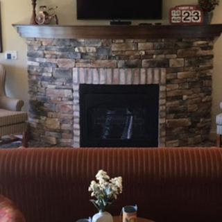 Cozy living room with a stone fireplace and TV above the mantel.