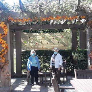 Two women enjoying a sunny day in a beautifully decorated garden area.
