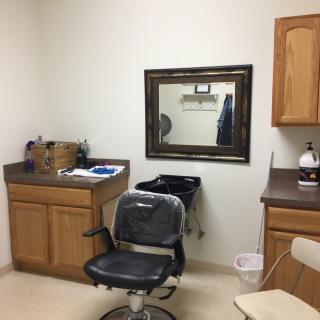 A barbershop interior with a chair, mirror, and cabinets.