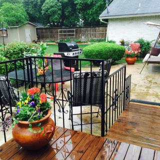 A cozy patio with a grill and colorful potted plants on a rainy day.
