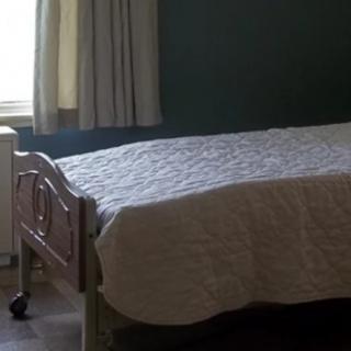 A hospital bed by a window with sunlight streaming in.