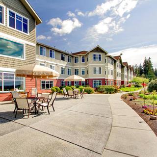 An exterior view of a large residential building with a landscaped garden and outdoor seating area.