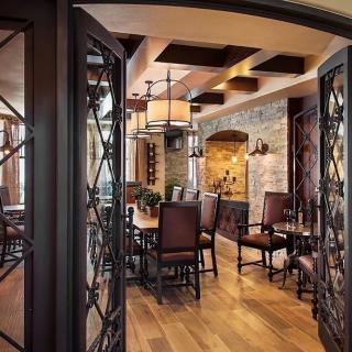 A luxurious dining area with wooden floors and stone walls, featuring elegant lighting and a wine cellar atmosphere.