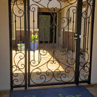 A beautifully designed decorative iron gate welcomes guests to the entrance of a home.