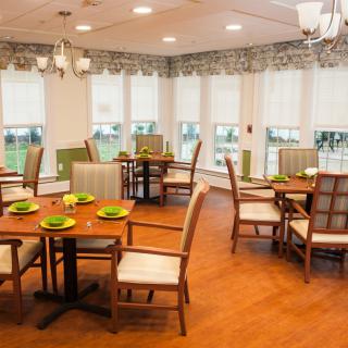 A well-lit dining room with elegant furniture and natural light streaming through large windows.