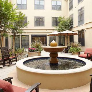 A serene courtyard featuring a central fountain surrounded by comfortable seating and lush greenery.