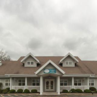 A commercial building with a prominent entrance under a cloudy sky.