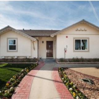 A charming single-story house with a brick pathway leading through a landscaped garden.