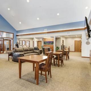A spacious lounge area with tables, chairs, a sofa, and a wall-mounted television.