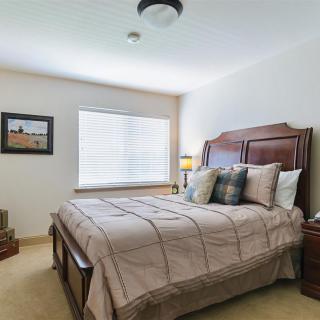 A cozy bedroom with a neatly made bed, bedside tables, and a window providing natural light.