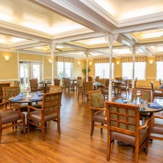 A spacious and well-lit restaurant dining area with neatly arranged tables and chairs.