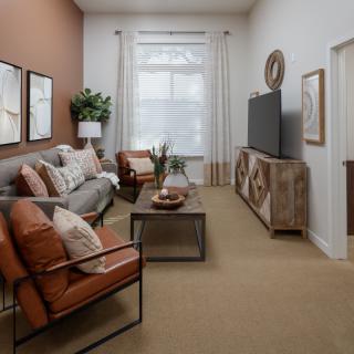 A modern living room featuring a comfortable sofa, armchairs, and a stylish TV stand with decorative elements.