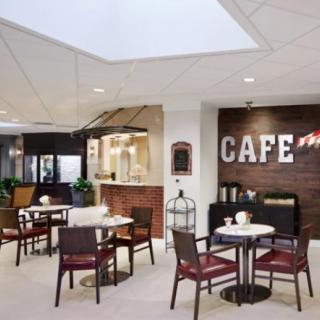 A modern cafe interior with tables and chairs, featuring a brick wall and stylish decor.