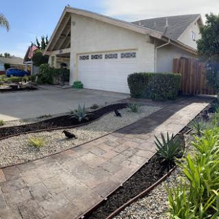 A well-maintained residential property featuring a landscaped front yard and a paved pathway leading to the house.