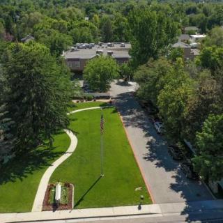 Aerial view of a park featuring a green lawn, winding pathways, and surrounding trees.