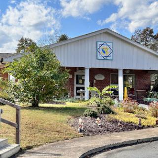 A welcoming building surrounded by a well-maintained garden under a partly cloudy sky.
