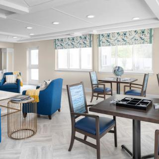A modern and bright interior featuring blue chairs and tables, with large windows letting in natural light.