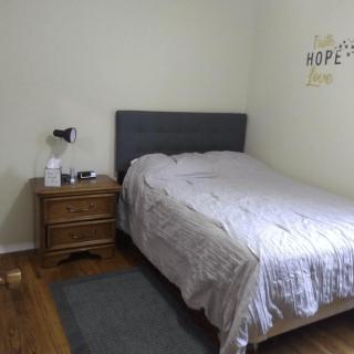 A cozy bedroom with a neatly made bed and a nightstand featuring a lamp and decor.