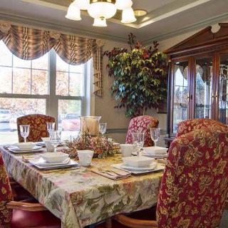 A cozy dining room with an elegantly set table and floral-patterned chairs.