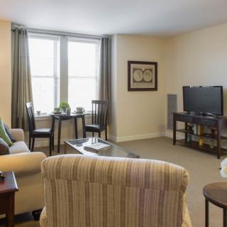 A cozy living room with comfortable seating, a television, and large windows.