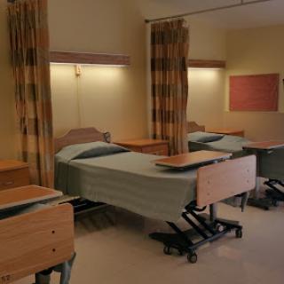 An interior view of a hospital patient room with multiple beds and curtains.