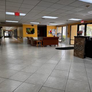 A spacious lobby area featuring comfortable seating and a reception desk, illuminated by natural light.