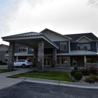A large two-story residential building with a driveway and a vehicle parked outside.