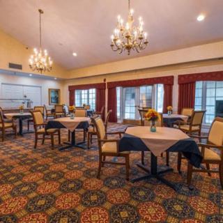 A spacious dining room with elegant chandeliers and neatly arranged tables and chairs.