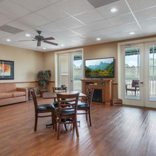 A cozy living room with a fireplace, TV, and comfortable seating area opens to a balcony.