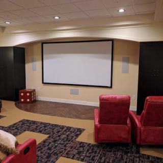 A cozy home theater setup featuring a projector screen and red seating.