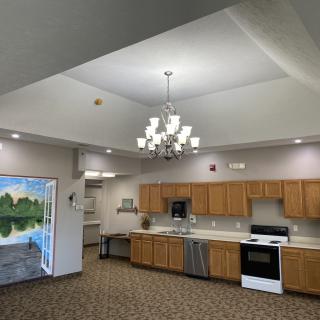 A modern kitchen with wooden cabinets, stainless steel appliances, and a decorative chandelier.