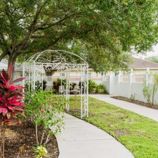 A peaceful garden pathway leading to a gazebo, surrounded by lush greenery.