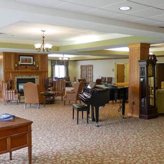 A spacious and elegantly furnished living area featuring a grand piano, comfortable seating, and a fireplace.