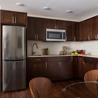 A modern kitchen with dark cabinets and stainless steel appliances.