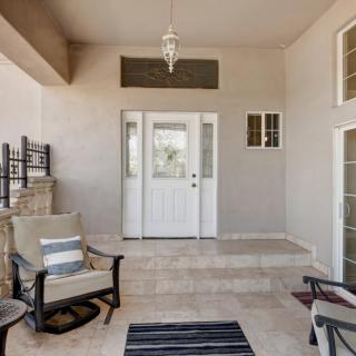 A cozy patio area with comfortable seating and decorative elements, leading to a white front door.