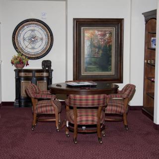 A small office area with a round table surrounded by four chairs, featuring wall art and decorative elements.