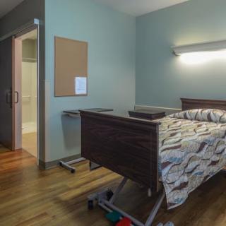 A hospital room featuring a bed and basic furnishings, designed for patient care.