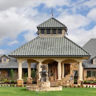 A beautifully designed house with a central gazebo featuring a tiled roof and stone columns.
