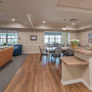 A spacious open floor plan featuring a living room and dining area with hardwood flooring, comfortable furniture, and a kitchen counter.