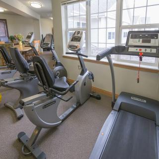 A fitness center featuring a treadmill and stationary bikes by a large window.