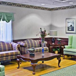 A cozy living room with plaid sofas, a wooden coffee table, and floral accents.
