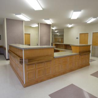 A spacious and well-lit reception area featuring a wooden counter and clean, modern design.