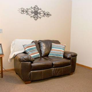 A cozy living room with a leather loveseat, decorated with striped pillows and wall decor.