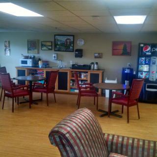 A cozy waiting room with chairs and tables, featuring a vending machine and a coffee station.