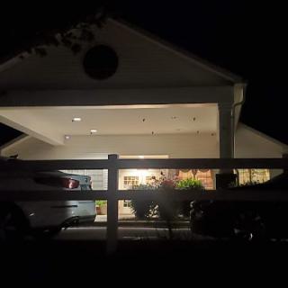 A well-lit house during the night, showcasing vehicles parked outside.