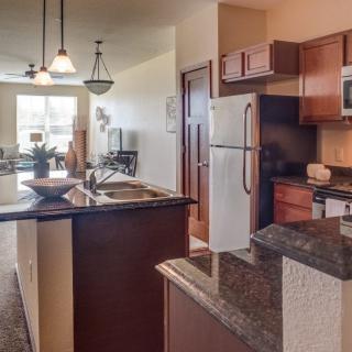 A modern kitchen in an apartment with wooden cabinets, granite countertops, and stainless steel appliances.