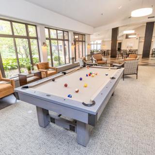 A modern recreational room featuring a billiard table and comfortable seating areas.