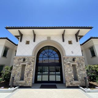 A modern building facade featuring a large arched window and stone accents.