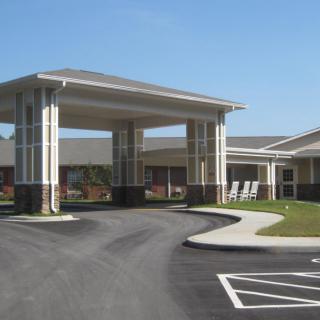 A building with a covered entrance and driveway under a clear blue sky.