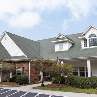 A suburban residential house with a green roof and brick exterior.